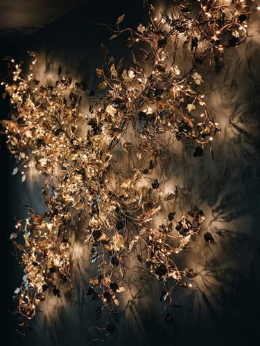 Moody editorial photograph of a large-scale illuminated ivy sculpture mounted on a dark plaster wall in a minimalist residence, warm golden micro-LEDs casting intricate organic shadows, low-key lighting, rich botanical textures, 35mm film.