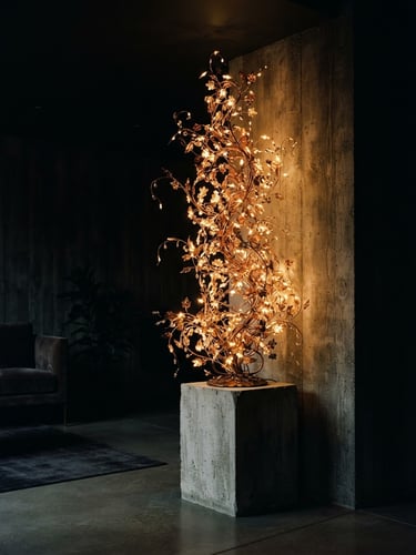 Moody editorial photography, low-key ambient lighting, a tall illuminated ivy sculpture glowing warmly in a dim, high-end minimalist concrete living room, soft shadows, 35mm film.
