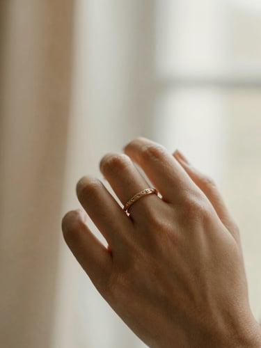 Close-up of a bride's hand wearing an intricate champagne-gold plated bridal ring set, soft diffused window light, muted cream and champagne tones, shallow depth of field, 35mm
