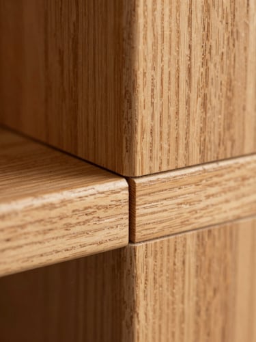 Macro close-up of a perfectly executed wood joint in warm oak, showing the fine grain and seamless technical alignment under soft natural daylight.