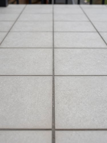 A crisp, close-up shot of perfectly aligned outdoor porcelain tiling joints on a Dublin patio, soft overcast Irish daylight, straight-on architectural lines showing structural precision.