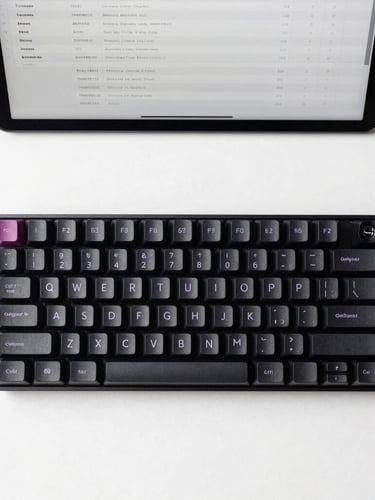 Straight-on flat lay of a minimalist mechanical keyboard and a clean tablet displaying structured database schemas, cool diffused studio lighting, crisp shadows