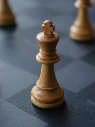 Macro shot of a minimalist wooden chess king on a dark navy surface, soft diffused daylight, architectural shadow play
