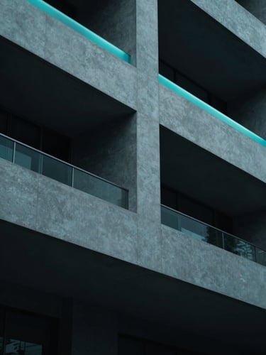 Minimalist architectural detail of a modern clinic facade, sharp geometric concrete lines under cool teal rim lighting, deep navy shadows, 35mm
