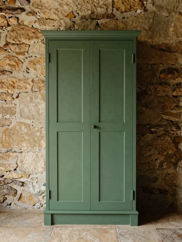 Straight-on architectural shot of a hand-painted forest green larder cabinet perfectly scribed to sit flush against an uneven historic stone cottage wall, soft morning light, warm editorial style, 35mm