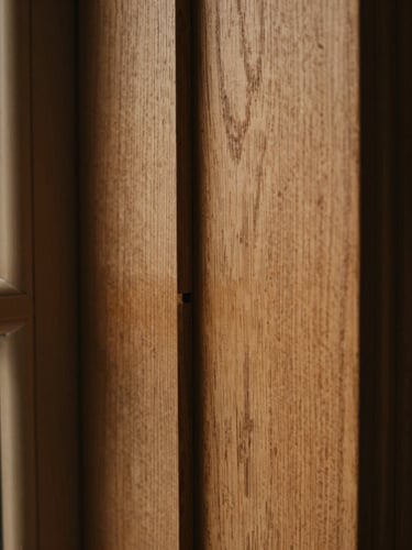 Macro close-up of architectural-grade wood joinery, mortise and tenon joint, rich oak wood grain, soft side-lit window light, deep shadows