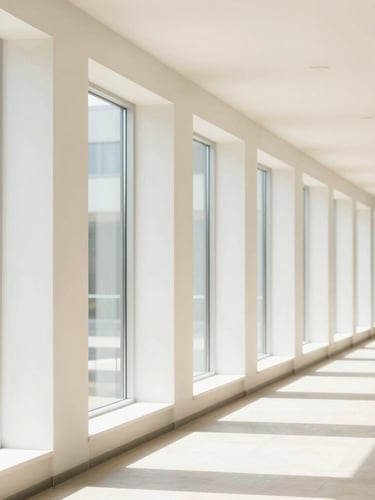 Bright modern architectural corridor with clean lines and floor-to-ceiling windows, high-key natural light.