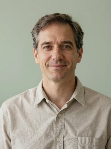 Portrait of a male psychologist in his early 40s, calm and friendly expression, natural light, soft green background, professional yet approachable, 35mm.