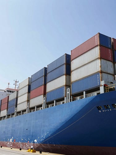 Wide-angle industrial shot of a massive blue container ship docked at Puerto Quetzal during bright daylight, high-contrast metallic surfaces, sharp details