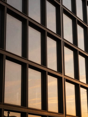 Extreme close-up of architectural steel and glass facade reflecting a golden sunset, deep bronze tones, sharp clean lines.
