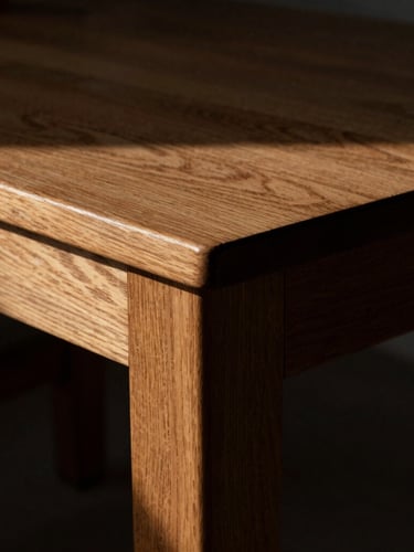 Tight macro shot of a heavy oak drafting table joint, dramatic side-lighting casting deep shadows, 35mm photography
