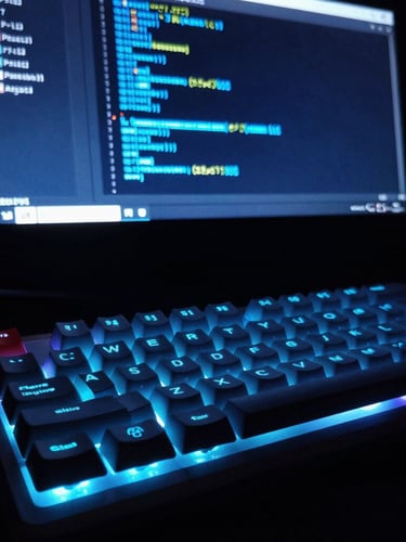 Dramatic low-angle macro shot of a glowing mechanical keyboard and a terminal screen running clean code blocks in neon blue, high-contrast, low-key lighting.