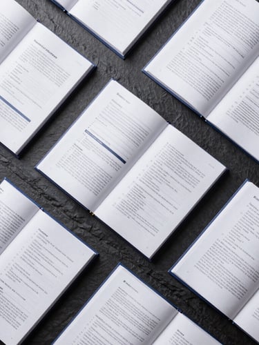 Top-down flat lay of highly structured, beautifully typeset technical manuals and corporate reports on a dark slate surface, sharp geometric alignment, crisp studio lighting