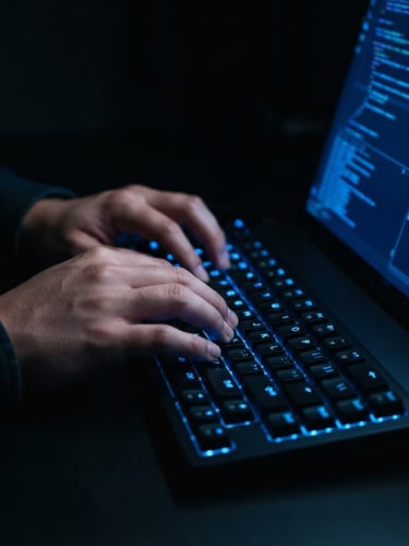 Sleek dark-mode technology photography, a macro shot of hands interacting with a glowing electric blue keyboard and screen, low-key studio lighting, deep obsidian tones