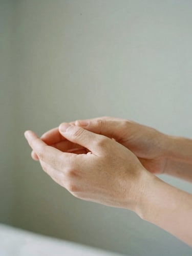 Close-up of hands performing a gentle applied kinesiology muscle assessment in a bright, sunlit room with muted sage walls, shallow depth of field, 35mm film