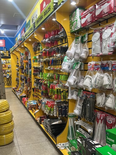 Corredor da Ferragista Central em Anápolis, GO, exibindo rolos de mangueira, prateleiras com tubos,