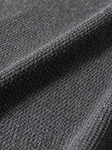 Studio close-up of a premium charcoal Reserva knit texture, showing clean geometric weave under soft neutral studio light.