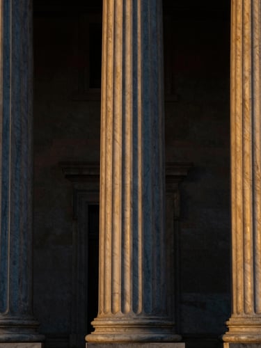 Elegant close-up of classical marble columns and architectural symmetry, dark low-key lighting, deep navy tones, golden highlights, 35mm lens