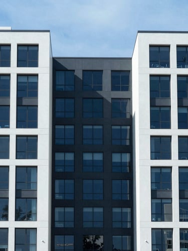 Symmetrical architectural crop of a modern South Florida commercial building facade, clean structural lines, bright daylight, cool blue and charcoal undertones