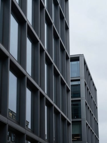 Architectural close-up of a modern corporate building facade with sharp steel and glass lines, cool overcast daylight casting soft shadows, 35mm editorial photography style.