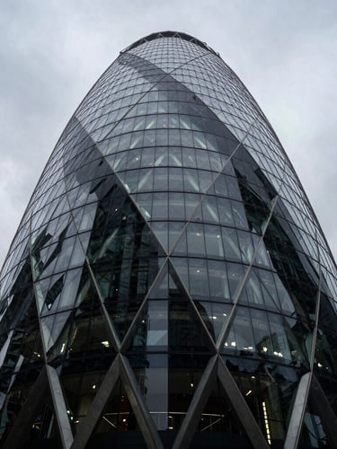 Extreme wide-angle dramatic architectural geometry of a modern financial tower in London, sharp overcast daylight, deep obsidian steel and glass facade, cold slate tones.