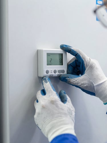 Close-up of technician hands in work gloves adjusting a digital thermostat on a commercial refrigerator, bright daylight, 35mm lens