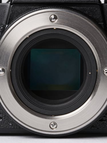 Macro close-up of a brushed aluminum camera lens mount, cool studio lighting with subtle blue reflections, clean technical framing.