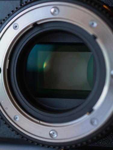 Macro close-up of a sleek camera lens mount with blue-toned rim lighting, high-contrast reflections, technical precision