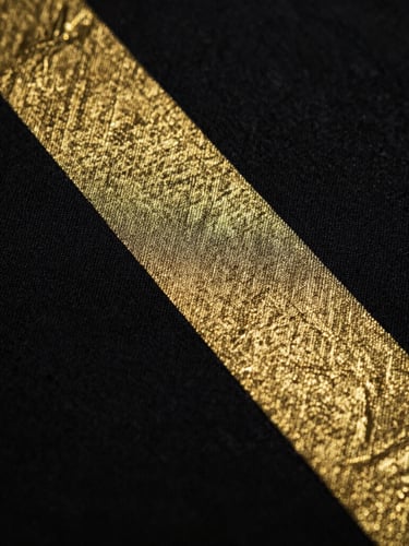 Macro shot of metallic gold DTF print texture on heavy black cotton fabric, low-key cinematic lighting, sharp details, 35mm lens