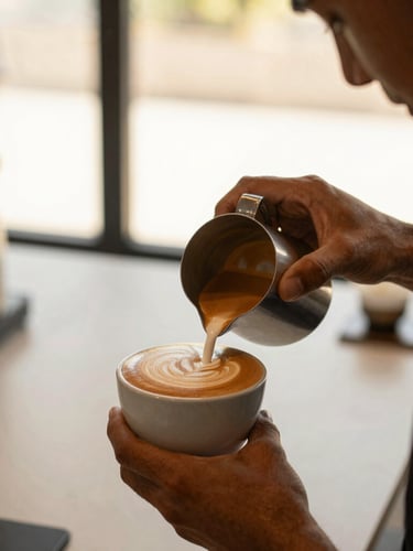 Close-up of a professional barista pouring intricate latte art into a ceramic cup at a modern, minimalist event, soft side-lighting, warm tones