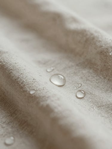 Macro shot of warm water droplets on clean linen, soft diffused natural light, misty atmosphere, warm neutral tones, 35mm