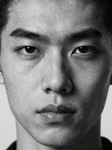 Extreme close-up portrait of a model with sharp, unconventional facial structure, stark studio strobe lighting, high-contrast black and white, raw skin texture visible, neutral expression