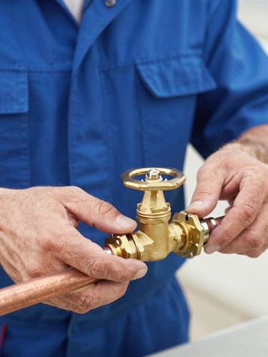 A close-up of a professional plumber's hands adjusting a brass valve on clean copper pipes, bright natural daylight, sharp focus, 35mm lens