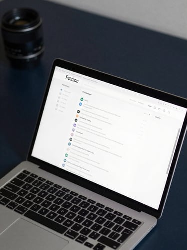 Close-up overhead flat-lay of a laptop screen showing a clean website dashboard interface, placed on a dark navy desk surface, minimal props, sharp studio lighting from above