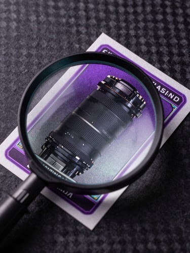 Top-down macro shot of a rare trading card being inspected with a magnifying glass, side-lit with neon violet highlights, deep textured carbon-fiber surface