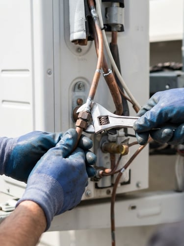 Close-up of a professional technician hands repairing a copper pipe of a minisplit air conditioner, bright natural daylight, high contrast blue and white tones, sharp focus
