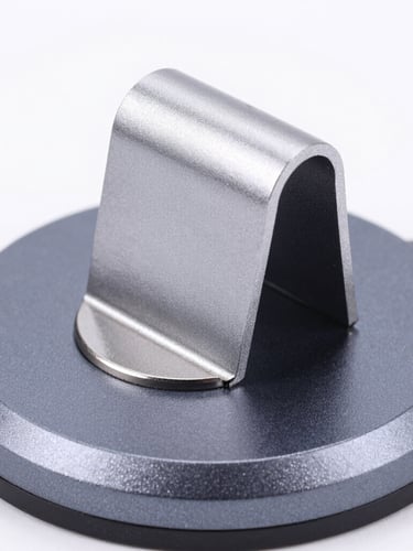 Macro product shot of a matte silver magnetic cable organizer snapping onto a deep charcoal anodized aluminum base, sharp studio strobe lighting, crisp highlights.