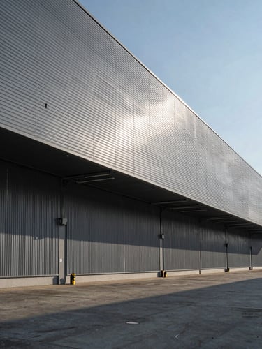 Wide imposing architectural perspective of a modern logistics terminal, sharp shadows, cool-toned daylight, high contrast, structural gray lines.