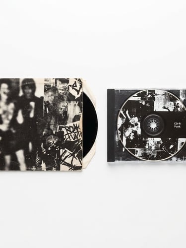 Straight-on flat lay of a rare punk rock vinyl sleeve and a CD jewel case on a pure white background, bright even studio lighting, sharp details