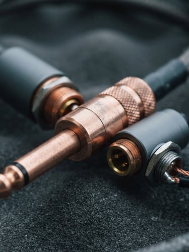 Tight macro shot of high-grade copper audio cable connectors, metallic textures, cool northern daylight, 35mm