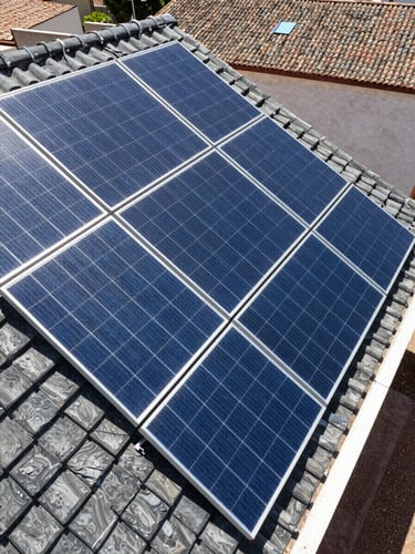 Close-up of clean modern solar panels installed on a residential tiled roof in Córdoba, bright daylight, high-contrast blue and slate tones, sharp technical photography