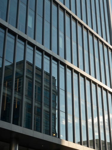 Modern architectural facade of a glass office building in Gaborone under bright daylight, clean lines, reflection of blue sky.