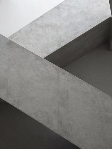 Architectural detail of a modern concrete staircase, clean lines, soft shadow play, minimalist luxury interior, monochromatic gray tones