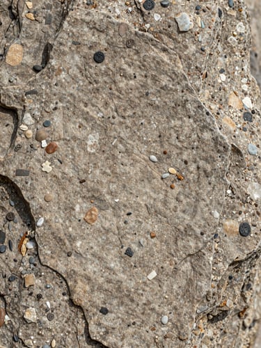 Macrophotographie de textures géologiques, roche sédimentaire fissurée avec des sédiments fins, lumière naturelle douce, mise au point sur les détails de la pierre.