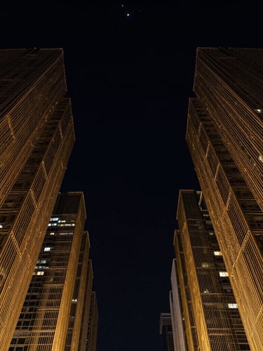 High-contrast low-key portrait of abstract gold-threaded architectural structures reaching toward a dark starry sky, cinematic lighting, 35mm