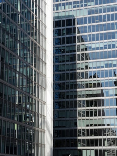 Abstract architectural lines of glass and steel skyscraper in London, sharp high-contrast shadows, bright daylight, clean editorial