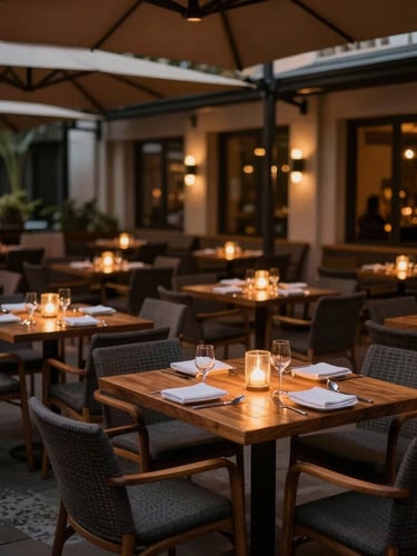 Wide environmental shot of a cozy heated outdoor restaurant terrace at dusk, soft warm golden lighting, elegant wooden tables, inviting atmosphere, 35mm