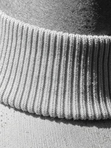 Extreme close-up macro shot of ultra-heavyweight cotton fabric texture, showing the tight structured weave and a flawless thick ribbed collar, high-contrast monochrome lighting highlighting the fibers