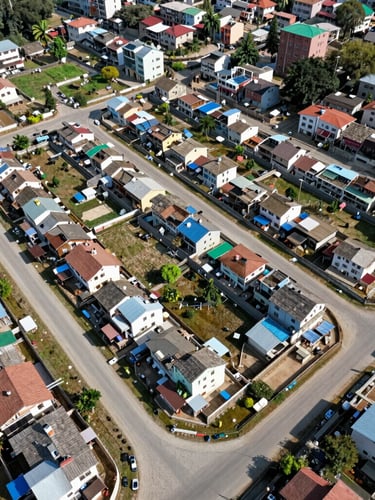Wide-angle aerial drone shot of structured residential land plotting in Pokhara, clear boundaries, gravel road access, bright daylight.