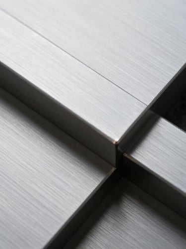 Abstract close-up texture of brushed silver metal and dark industrial stone, sharp geometric lines, cool overcast lighting.